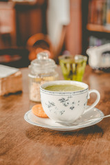 green tea matcha soy latte in a china cup with brown sugar and a glass of water on the side