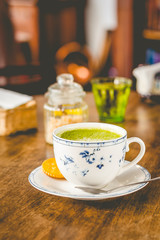 green tea matcha soy latte in a china cup with brown sugar and a glass of water on the side