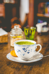 green tea matcha soy latte in a china cup with brown sugar and a glass of water on the side