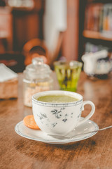green tea matcha soy latte in a china cup with brown sugar and a glass of water on the side