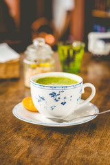 green tea matcha soy latte in a china cup with brown sugar and a glass of water on the side