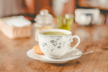 green tea matcha soy latte in a china cup with brown sugar and a glass of water on the side