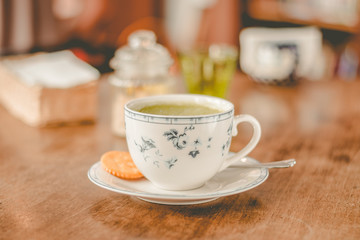 green tea matcha soy latte in a china cup with brown sugar and a glass of water on the side