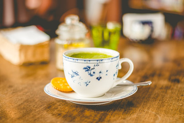 green tea matcha soy latte in a china cup with brown sugar and a glass of water on the side