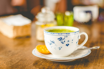 green tea matcha soy latte in a china cup with brown sugar and a glass of water on the side