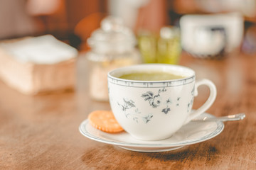 green tea matcha soy latte in a china cup with brown sugar and a glass of water on the side