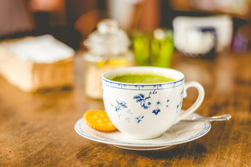 green tea matcha soy latte in a china cup with brown sugar and a glass of water on the side