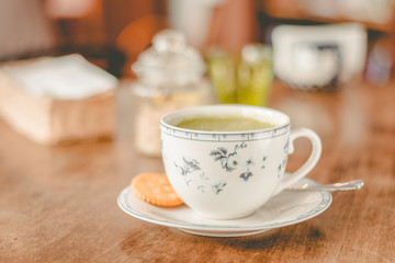 green tea matcha soy latte in a china cup with brown sugar and a glass of water on the side