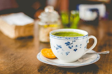 green tea matcha soy latte in a china cup with brown sugar and a glass of water on the side
