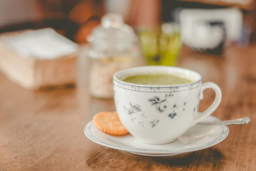 green tea matcha soy latte in a china cup with brown sugar and a glass of water on the side