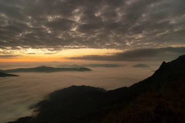 Obraz premium Mountain view morning of top hill around with sea of mist in valley with orange sun light and cloudy sky background, sunrise at Pha Tang, Chiang Rai, northern of Thailand.