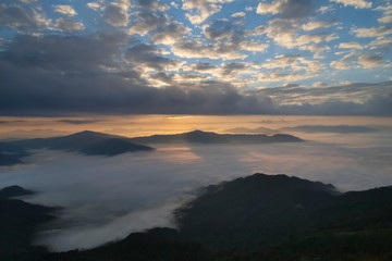 Mountain view morning of top hill around with sea of mist in valley with orange sun light and cloudy sky background, sunrise at Pha Tang, Chiang Rai, northern of Thailand.