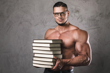Smart and muscular man with a heap of books
