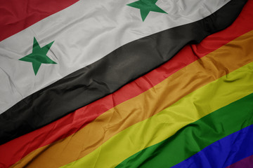 waving colorful gay rainbow flag and national flag of syria.