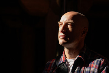 portrait of a bald man in a dark room hard shadows