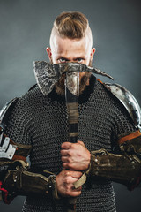 Medieval warrior berserk Viking with tattoo and in skin with axes attacks enemy. Concept historical photo