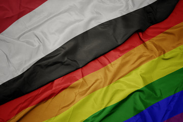 waving colorful gay rainbow flag and national flag of yemen.