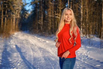 beautiful happy blonde woman in red sweater in winter forest