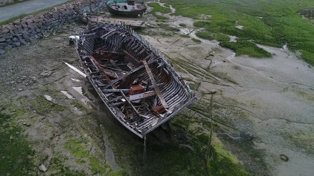 Aerial view. Skeleton of an old abandoned wooden boat. Cemetery of dead ships. Broken deserted vessel aground. Top view by drone.