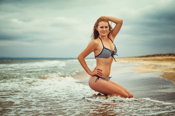 beautiful young woman in swimsuit on the beach posing sitting