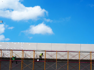 Construction workers working on scaffolding with blue sky at construction site