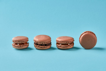 Obraz na płótnie Canvas Close-up studio shot of tasty chocolate macarons on blue background.