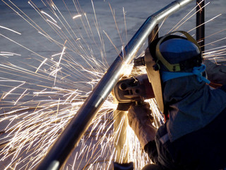 Worker grinds the Steel of angular grinding machine