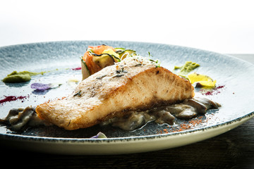 closeup baked sea fish steak served on fried mushrooms
