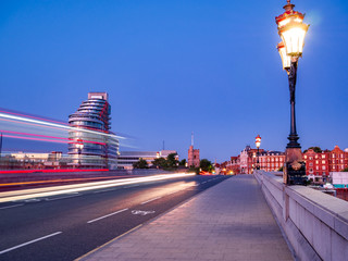 Red double decker bus trails on Putney bridge agains blue sky in London