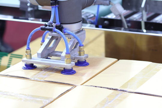 The robot arm transfers carton box  to conveyor line