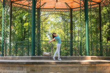 Young woman posing in the beautiful green garden pavilion. Mestsky or City park of Kosice, Slovakia (Slovensko). People, travel and summer holidays concept