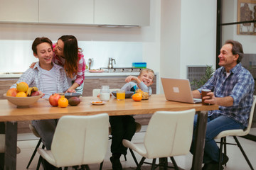 Mature parents and their children have a homemade breakfast together, they are very hungry eating the food and feeling so happy that they are together in a modern kitchen design