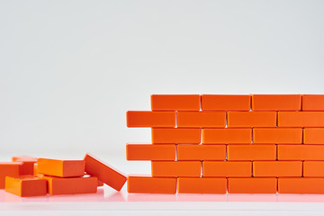 Broken wall made of toy blocks on a white background