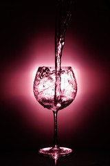Pouring water into glass , black background and red light