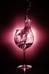 Pouring water into glass , black background and red light