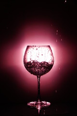 Pouring water into glass , black background and red light