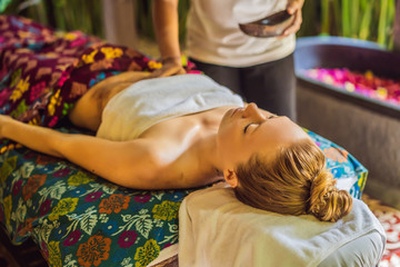 Young beautiful relaxing woman getting spa massage of shoulder in beauty salon
