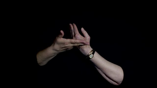 A pair of diverse hands connecting in a spiritual way on dark black background Conman looks like fake sign language &  bad tai chi movements. Calming soothing relaxing hand gestures religious ceremony
