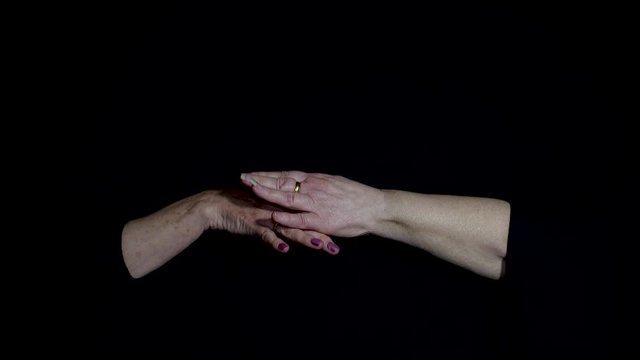 A pair of diverse hands connecting in a spiritual way on dark black background Conman looks like fake sign language &  bad tai chi movements. Calming soothing relaxing hand gestures religious ceremony