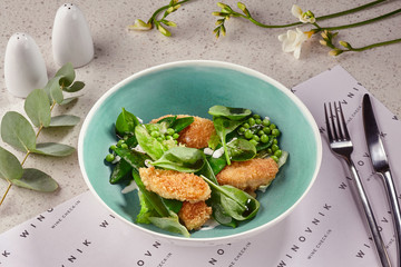 Fried breaded crispy chicken slices in a blue plate served on a table with a white tablecloth.