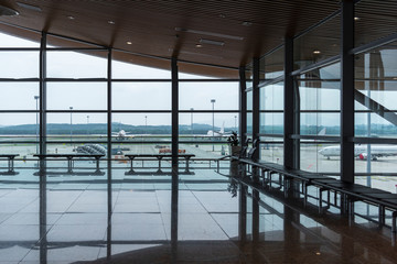 International airport interior corridor with seats and glass frame and reflections window in...