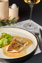 Delicious fish cooked in an oven and garnished with sauce and cabbage.