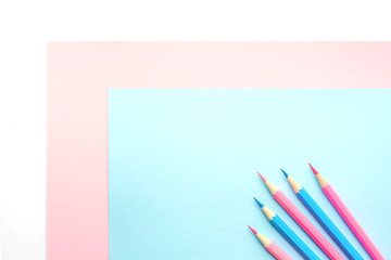 Pink and blue pencils and paper on white background. Top view, flat lay composition, frame, layout. Copy space for text or design.