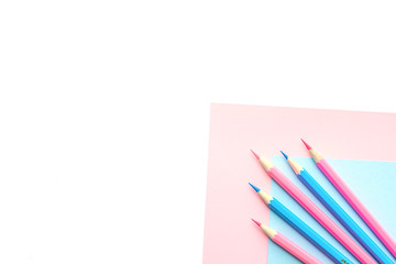 Fototapeta premium Pink and blue pencils and paper on white background. Top view, flat lay composition, frame, layout. Copy space for text or design.