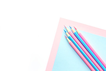 Pink and blue pencils and paper on white background. Top view, flat lay composition, frame, layout. Copy space for text or design.