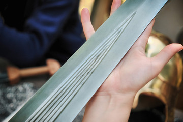 Close-up ancient Roman sword blade in the woman's hand. The girl holds the sword in her palm, close-up.