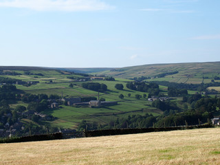 Naklejka premium a scenic view of west yorkshire countryside with the village of luddenden at the bottom of the calder valley with buildings surrounded by farms and fields