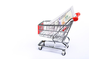 Shopping cart with one hundred US dollar bills isolated on white background.