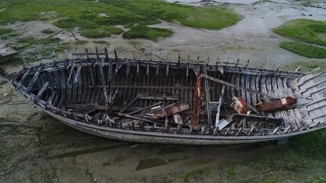 Aerial view. Skeleton of an old abandoned wooden boat. Cemetery of dead ships. Broken deserted vessel aground. Top view by drone.