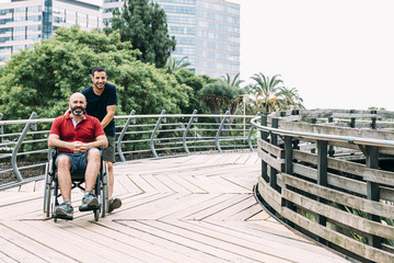 man in wheelchair walks with a friend in the park